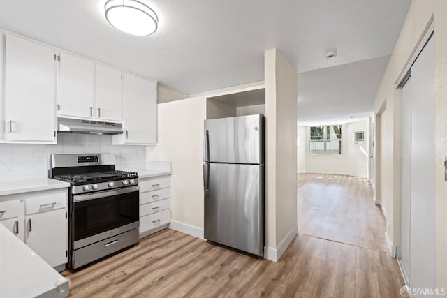 kitchen featuring light wood-type flooring, stainless steel appliances, white cabinetry, and tasteful backsplash