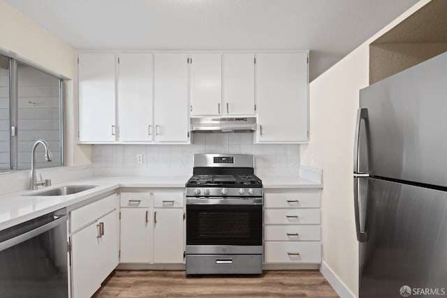 kitchen with appliances with stainless steel finishes, white cabinetry, tasteful backsplash, and sink