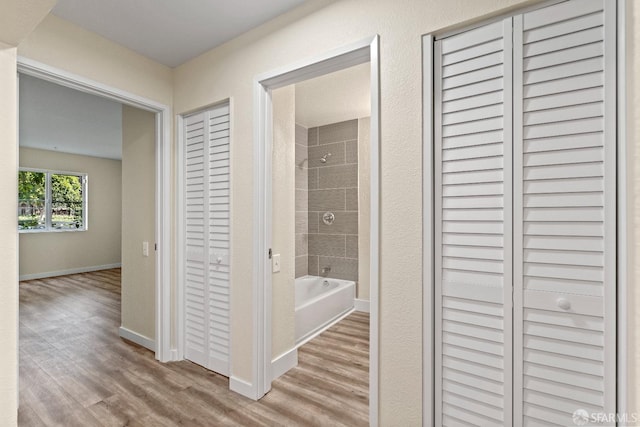 bathroom with hardwood / wood-style flooring and tiled shower / bath