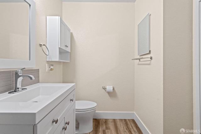 bathroom with toilet, vanity, and wood-type flooring