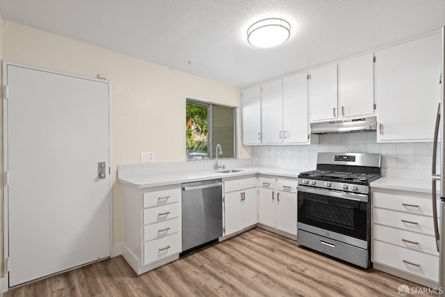 kitchen featuring a textured ceiling, white cabinetry, stainless steel appliances, decorative backsplash, and sink