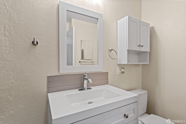 bathroom with toilet, vanity, and decorative backsplash