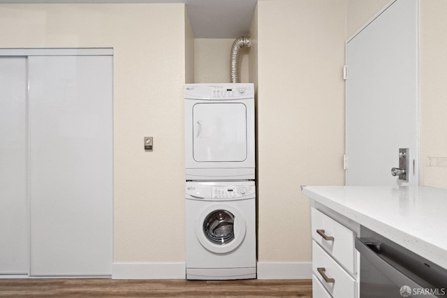 laundry room with hardwood / wood-style flooring and stacked washer and clothes dryer