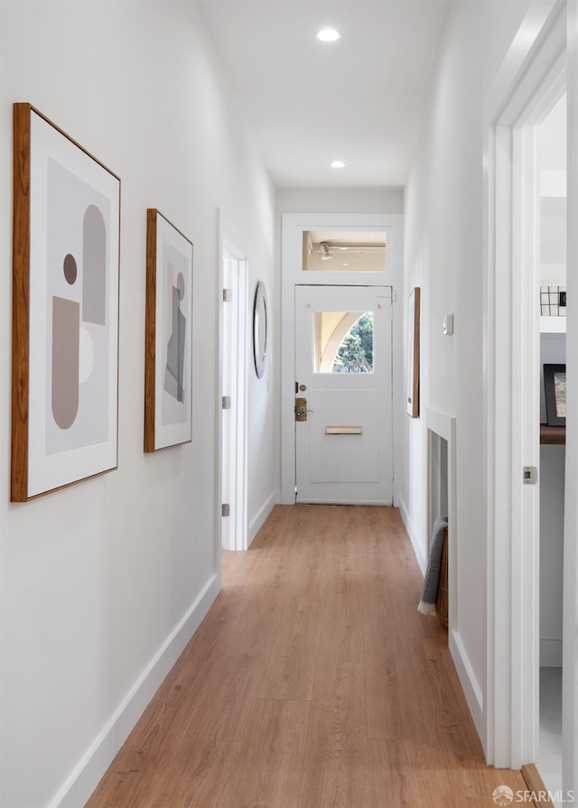corridor featuring baseboards, light wood finished floors, and recessed lighting