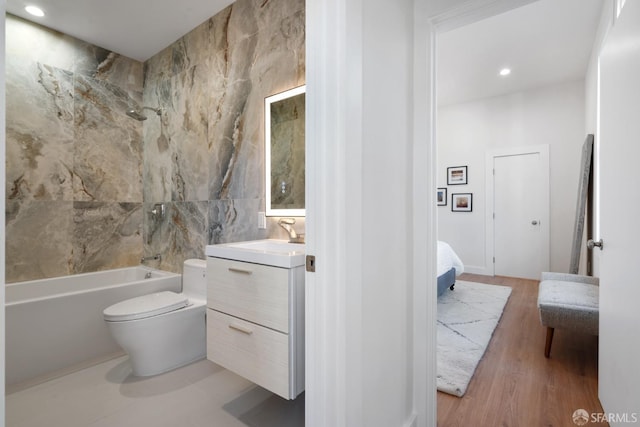 ensuite bathroom with vanity, toilet, shower / bathtub combination, tile walls, and wood finished floors