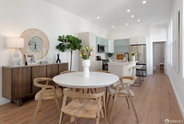 dining space with light wood-type flooring, baseboards, and recessed lighting