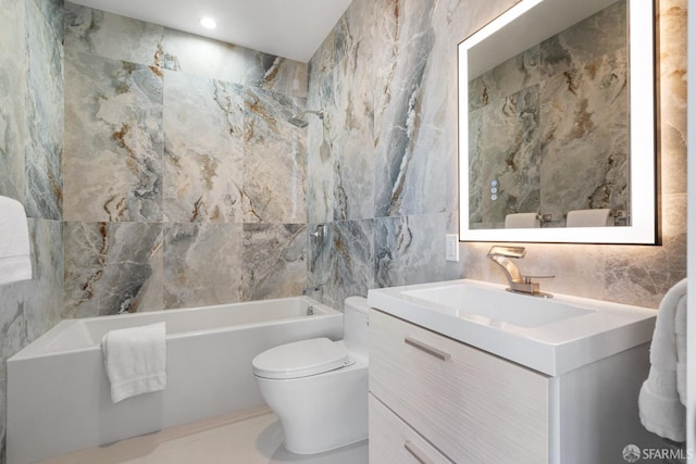 bathroom featuring toilet, vanity, bathtub / shower combination, and tile walls