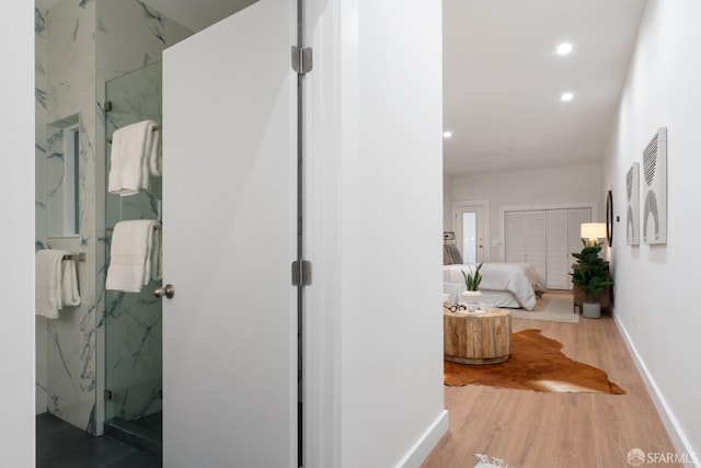 corridor with wood finished floors, baseboards, and recessed lighting