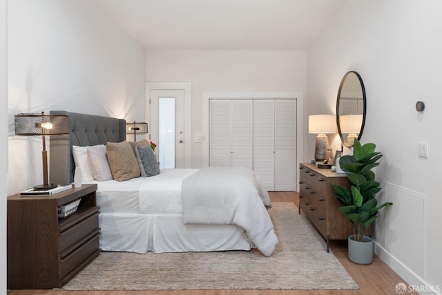bedroom with light wood-style floors, a closet, and baseboards