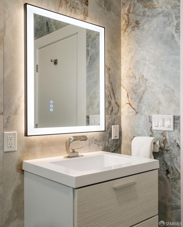half bath featuring vanity and tile walls