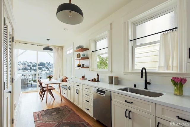 kitchen with pendant lighting, sink, dishwasher, white cabinetry, and dark hardwood / wood-style floors