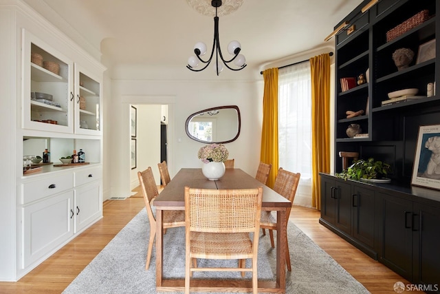 dining space featuring built in shelves, an inviting chandelier, and light hardwood / wood-style floors