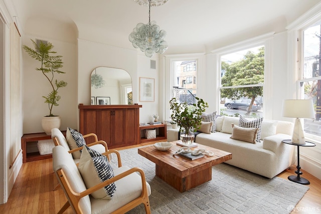 living room with plenty of natural light, a chandelier, and light hardwood / wood-style flooring