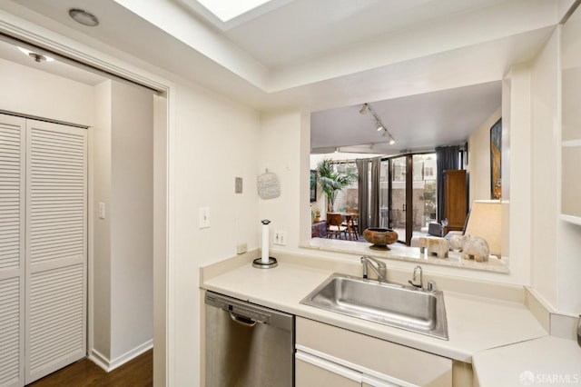 kitchen featuring sink, track lighting, dark wood-type flooring, and stainless steel dishwasher