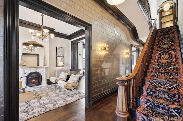 stairway featuring hardwood / wood-style floors, crown molding, tile walls, and an inviting chandelier