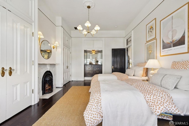 bedroom with a high end fireplace, dark hardwood / wood-style floors, and a chandelier