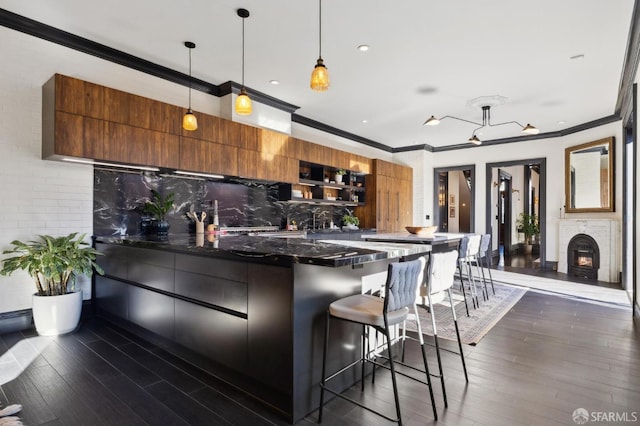 kitchen with pendant lighting, a breakfast bar area, dark stone countertops, backsplash, and dark hardwood / wood-style floors