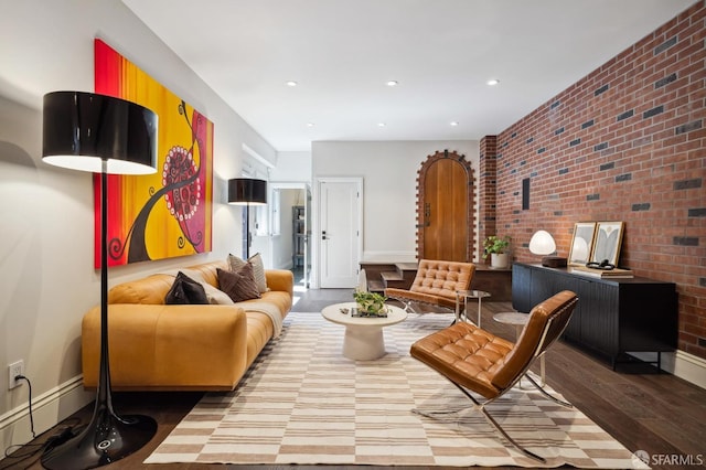 living area with brick wall and wood-type flooring