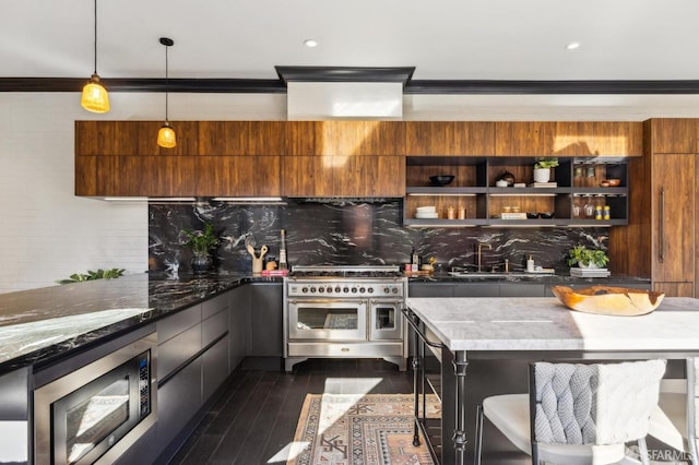 kitchen featuring pendant lighting, decorative backsplash, stainless steel appliances, and a kitchen breakfast bar