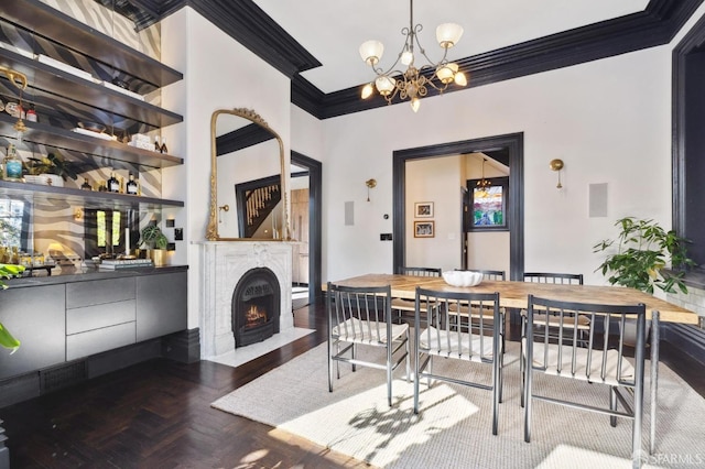 dining area with dark parquet flooring, a chandelier, and crown molding