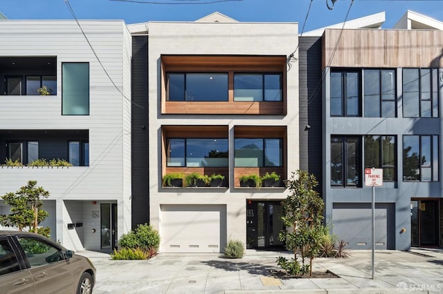 view of front of home with a garage, driveway, and stucco siding