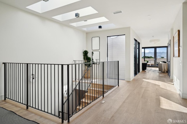 corridor with a skylight, baseboards, visible vents, wood finished floors, and french doors