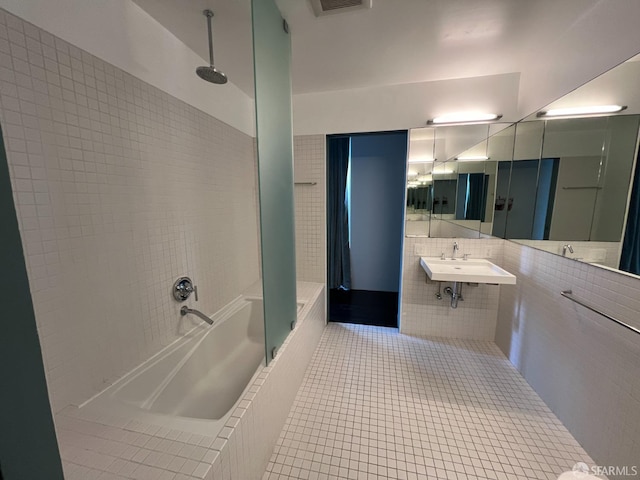 bathroom with tile patterned flooring, sink, tile walls, and tiled shower / bath