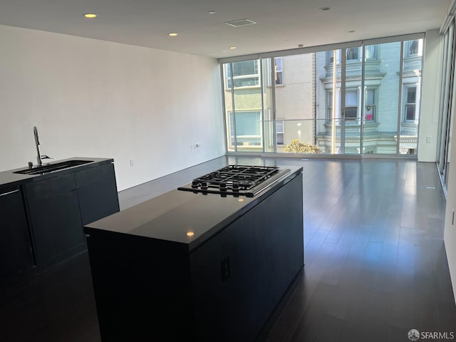 kitchen with sink, a wall of windows, dark hardwood / wood-style flooring, an island with sink, and stainless steel gas stovetop