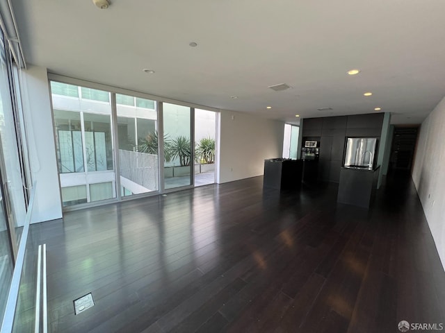 unfurnished living room with dark hardwood / wood-style floors and a wall of windows