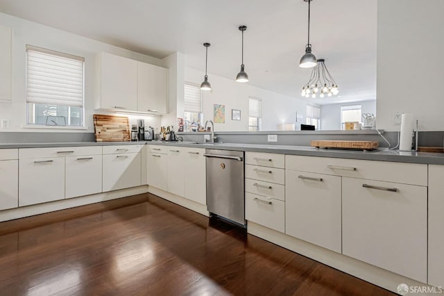 kitchen with stainless steel dishwasher, dark wood finished floors, a sink, and decorative light fixtures
