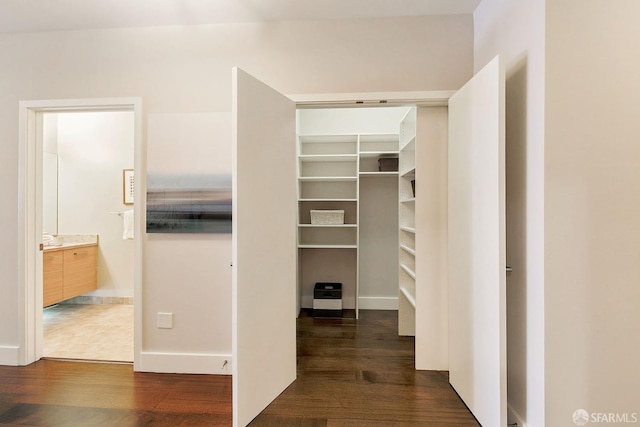 walk in closet with dark wood-style flooring
