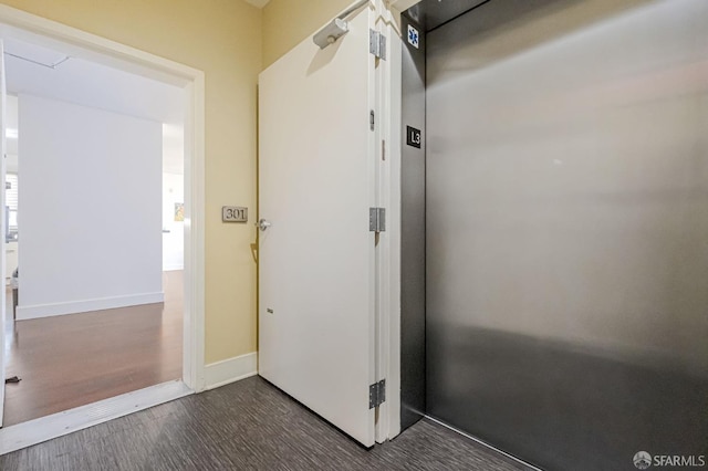 doorway with dark wood-style flooring, elevator, and baseboards