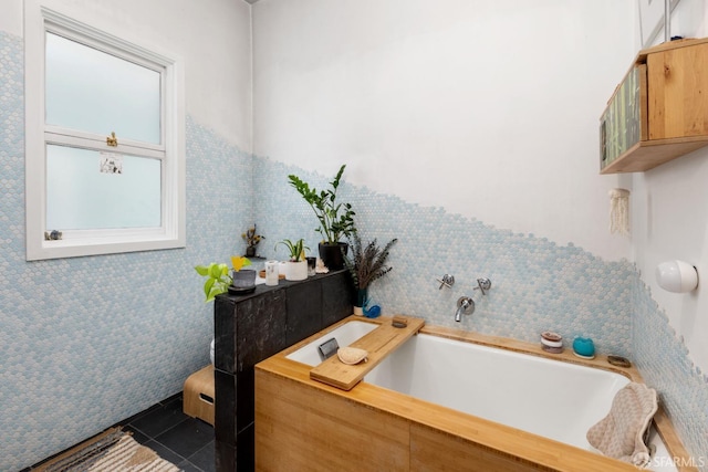 bathroom featuring tile patterned flooring, a washtub, and tile walls