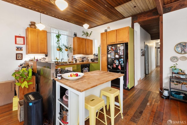 kitchen featuring black refrigerator, sink, dark hardwood / wood-style floors, butcher block countertops, and hanging light fixtures