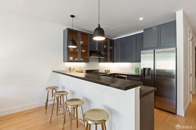 kitchen with stainless steel appliances, kitchen peninsula, hanging light fixtures, and a breakfast bar area