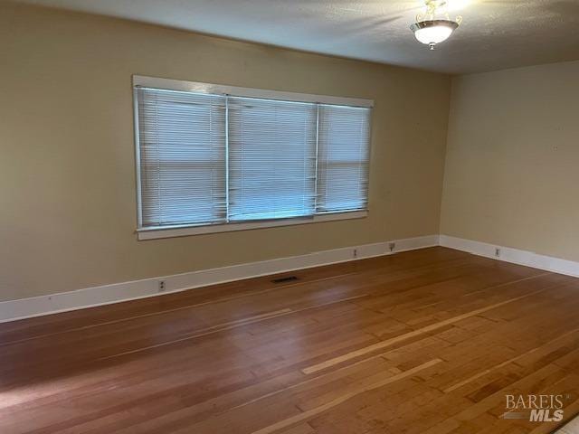 unfurnished room featuring hardwood / wood-style flooring and a textured ceiling