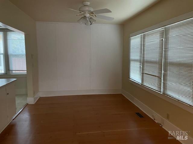 unfurnished room with dark wood-type flooring and ceiling fan