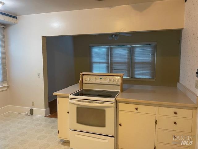 kitchen with white cabinets, kitchen peninsula, and electric range