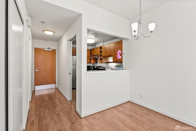 kitchen featuring decorative light fixtures, stainless steel refrigerator, a chandelier, and light wood-type flooring