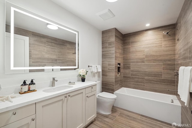 full bathroom with vanity, tiled shower / bath, and toilet