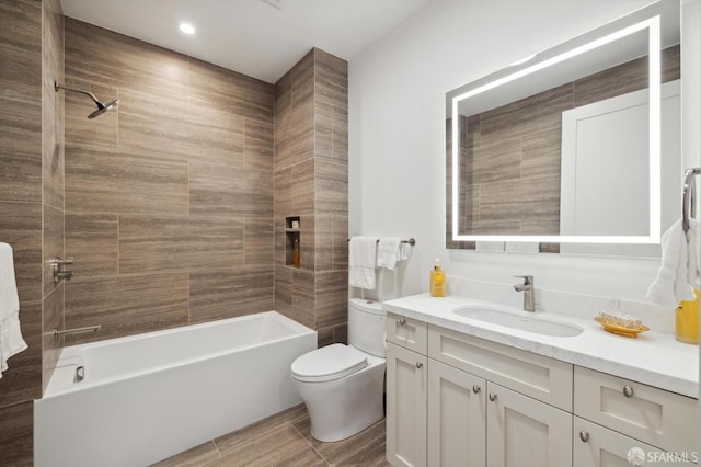 full bathroom featuring tiled shower / bath combo, vanity, and toilet