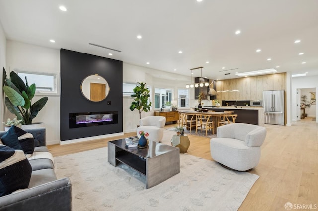 living room featuring a large fireplace, a healthy amount of sunlight, and light hardwood / wood-style floors