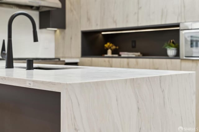 interior details with range hood, sink, and light brown cabinets