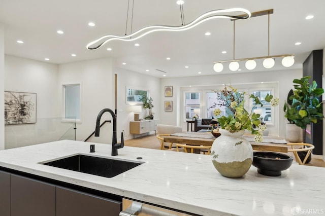 kitchen featuring light stone counters, decorative light fixtures, and sink