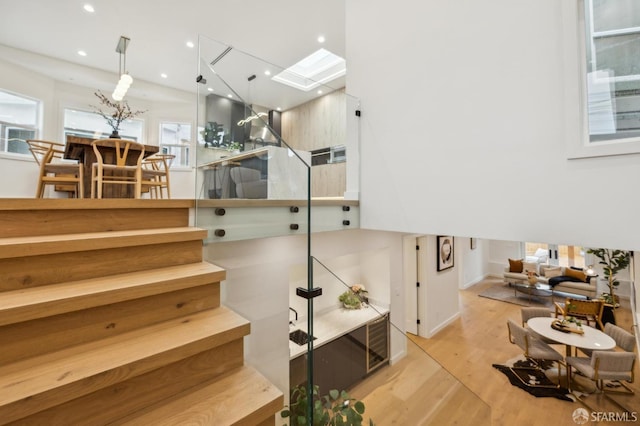 stairs with wood-type flooring, a skylight, and plenty of natural light