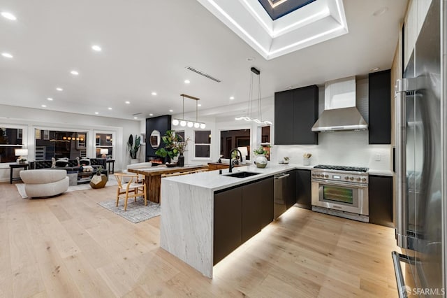 kitchen featuring open floor plan, wall chimney range hood, modern cabinets, high quality appliances, and a peninsula