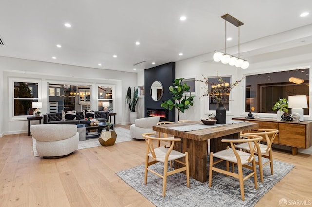 dining area featuring light wood-style floors, recessed lighting, a large fireplace, and baseboards