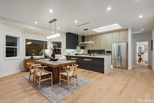 dining area with light wood finished floors, a skylight, baseboards, visible vents, and recessed lighting