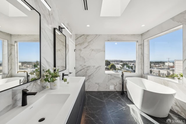 full bath featuring a skylight, marble finish floor, and stone wall