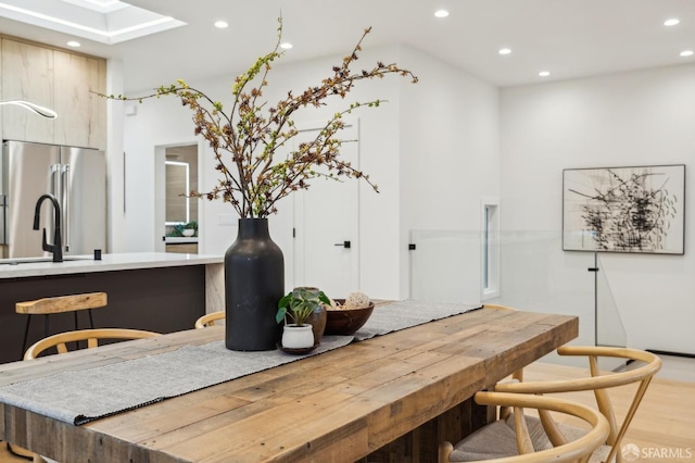 dining area with sink, light wood-type flooring, and a skylight